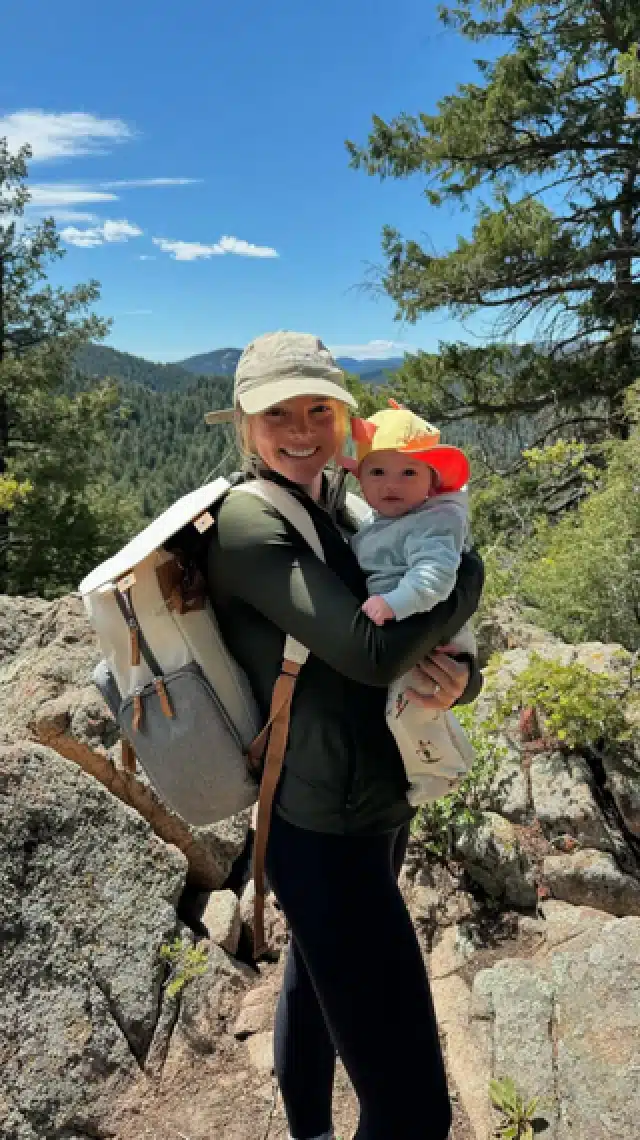 a woman holding a baby on a rocky mountain